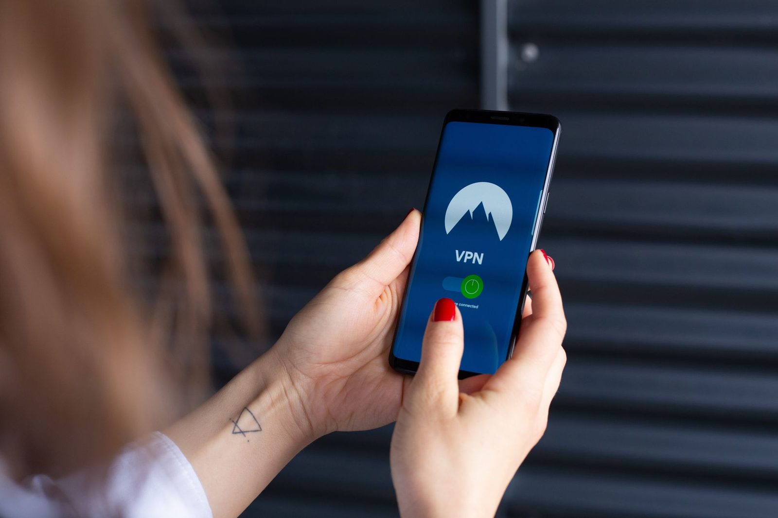 امرأة تحمل هاتفاً ذكياً يظهر على شاشته تطبيق VPN مفعّل