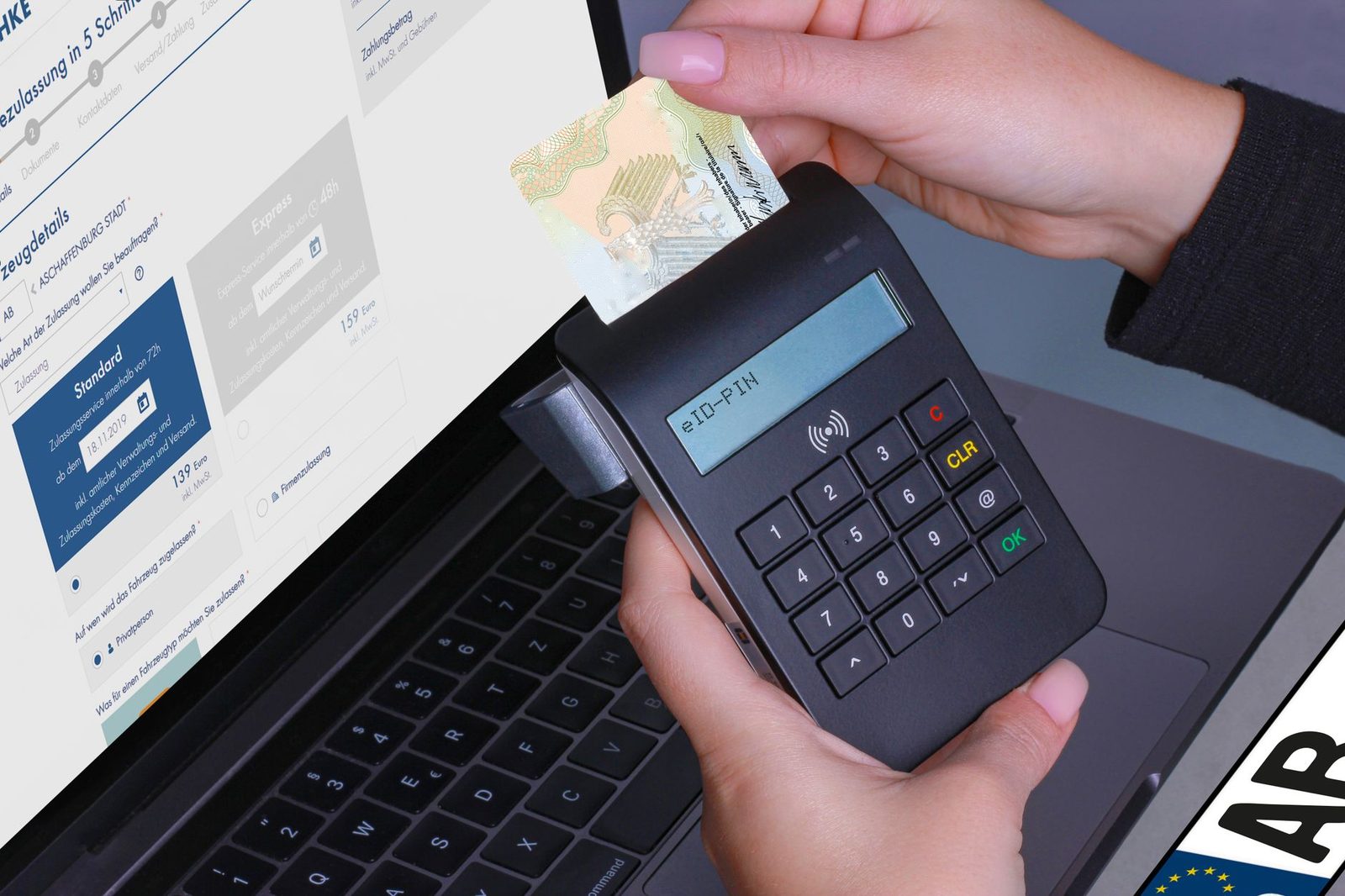 Hand steckt einen elektronischen Personalausweis in ein eID-Lesegerät mit PIN-Eingabe vor einem Laptop