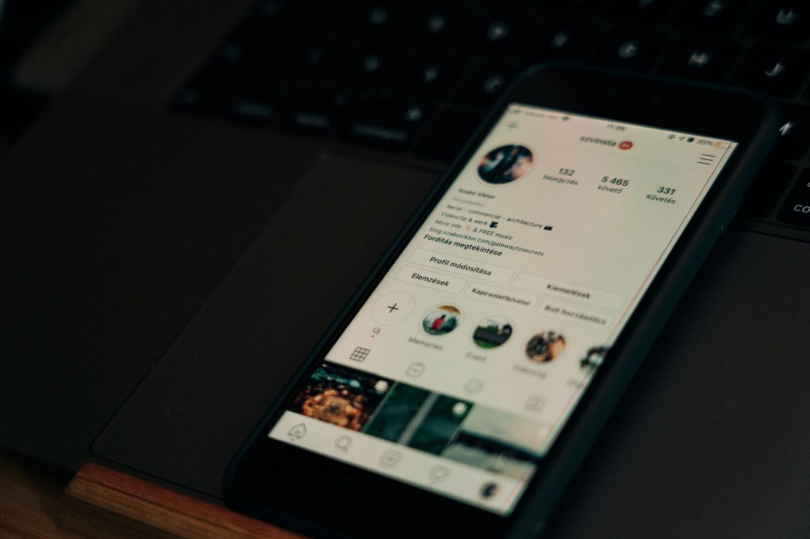Smartphone posé sur un clavier d'ordinateur portable affichant un profil de réseau social
