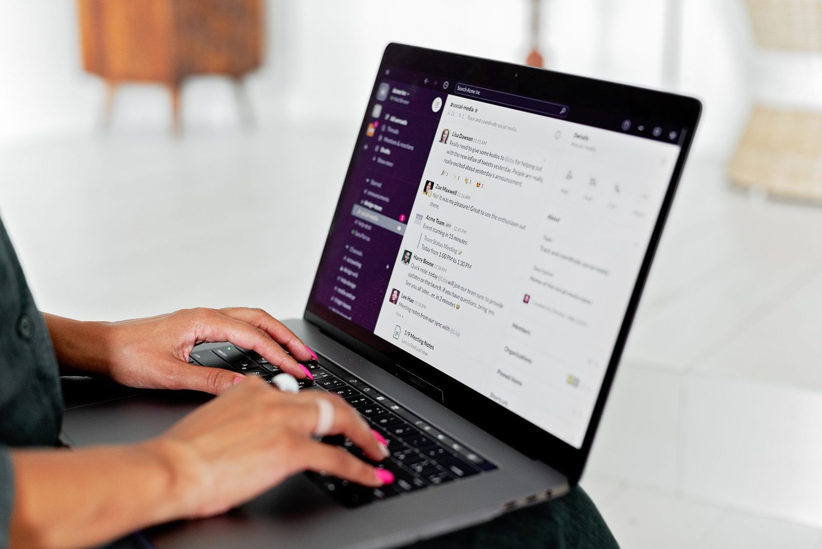 Femme tapant sur un ordinateur portable affichant une messagerie d'équipe avec des conversations en ligne