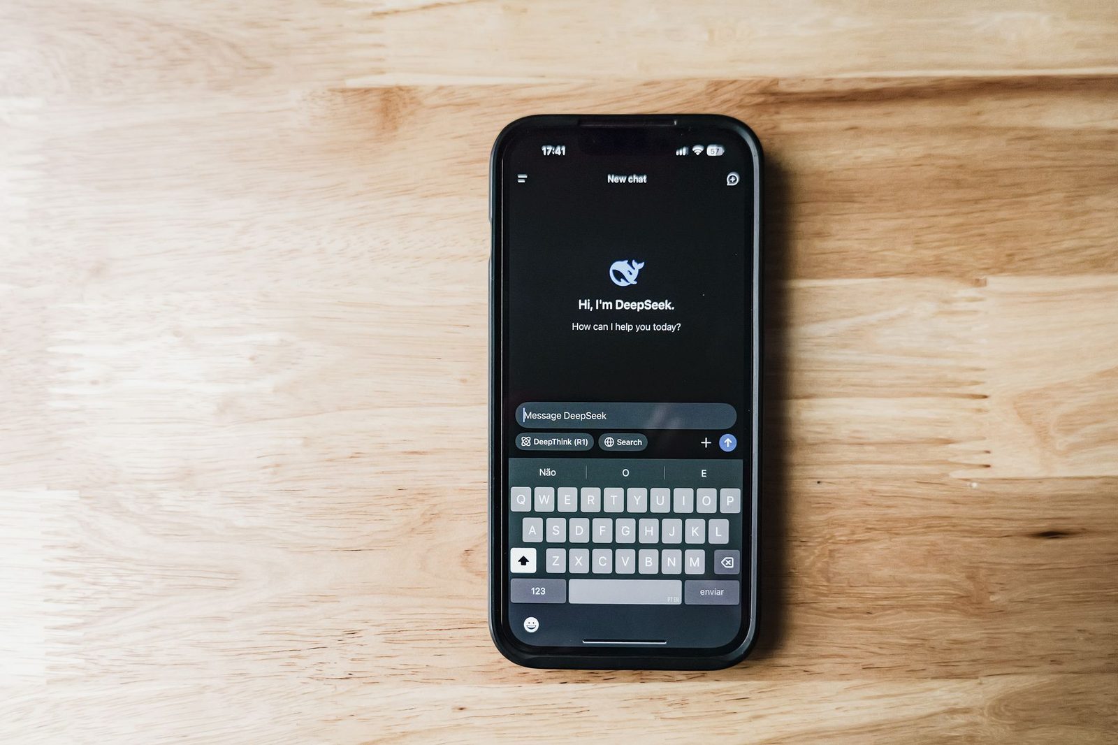 Smartphone posé sur une table en bois affichant l'interface de discussion de l'assistant IA DeepSeek