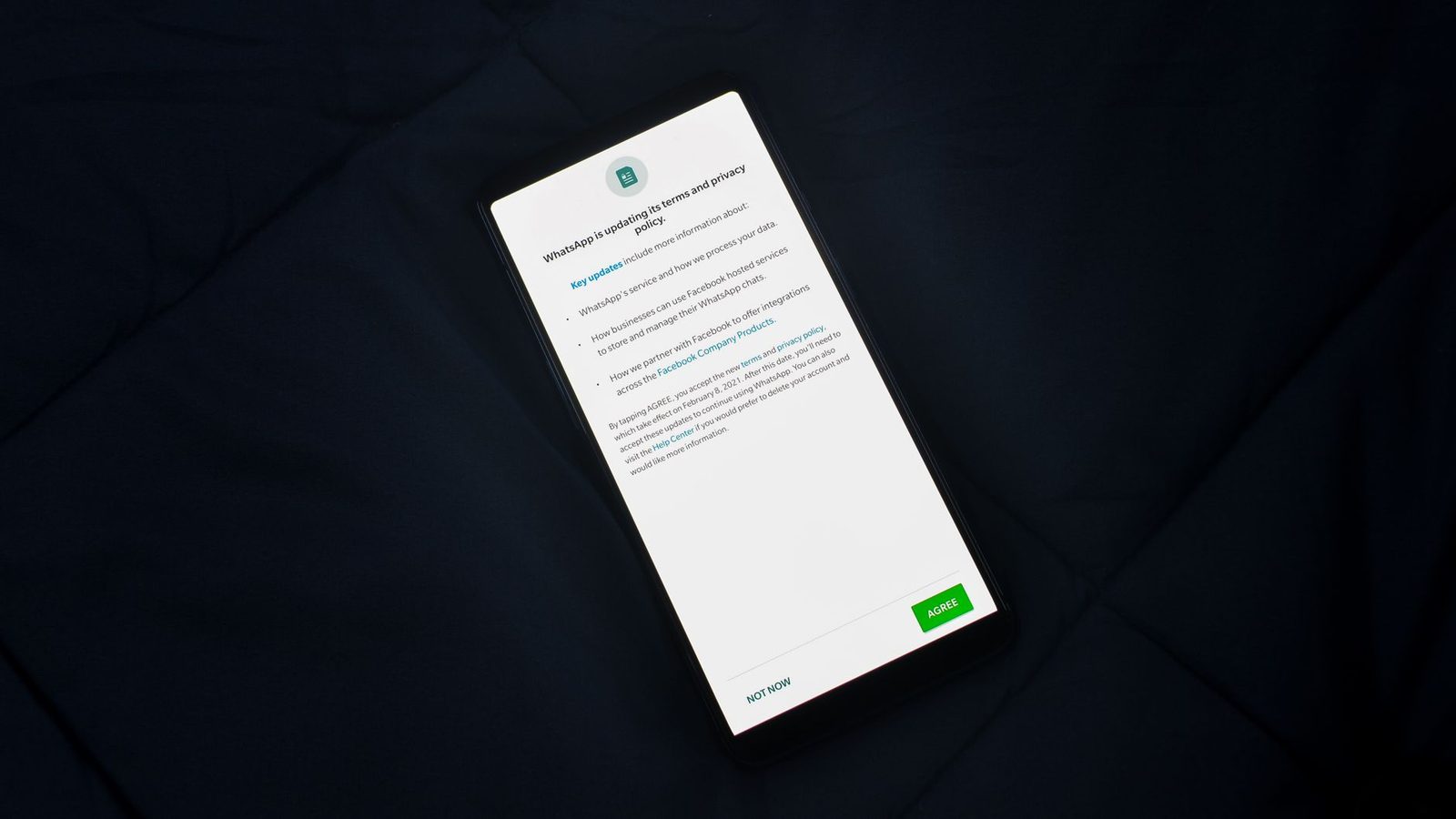 Smartphone posé sur un tissu sombre affichant une mise à jour de la politique de confidentialité d'une messagerie