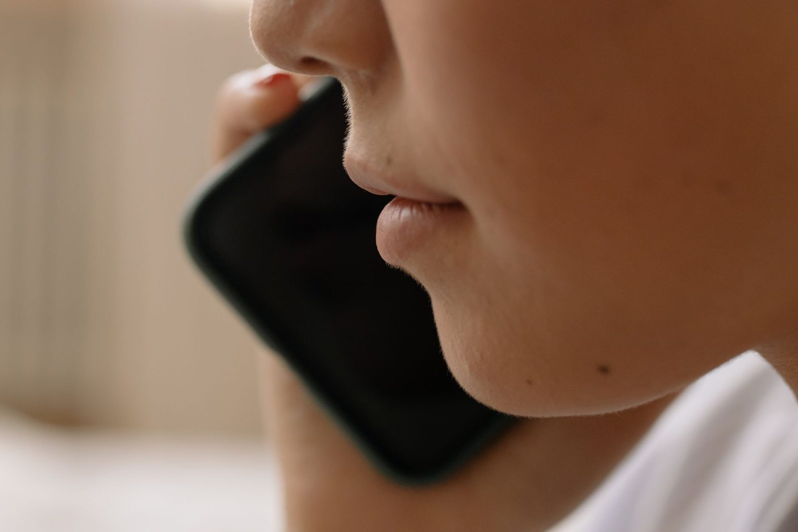 Close-up of a person's face holding a black smartphone to their ear during a call