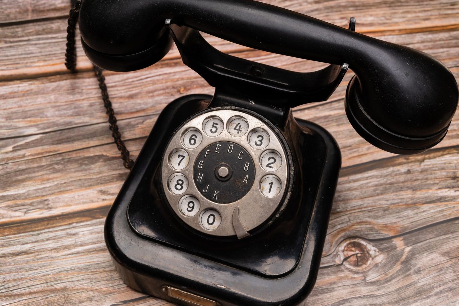 Ancien téléphone noir à cadran rotatif posé sur des planches de bois usées